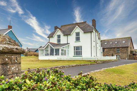 A photograph of Rocksdrift House taken from the seafront showing the lawn down to the seafront and the Coach House behind.