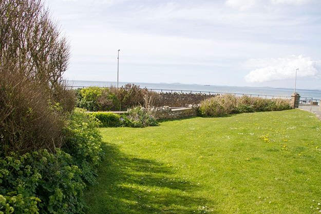 Mature garden around apartments leading down to the sea in the background.